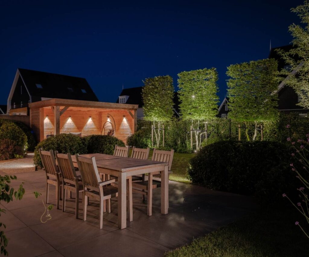 Luxe verlichte achtertuin met terras, tuin en overkapping